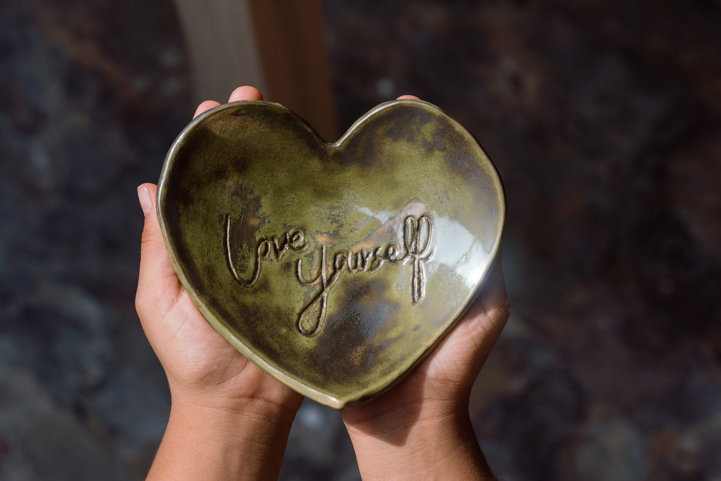 Child holding Love yourself ceramic heart